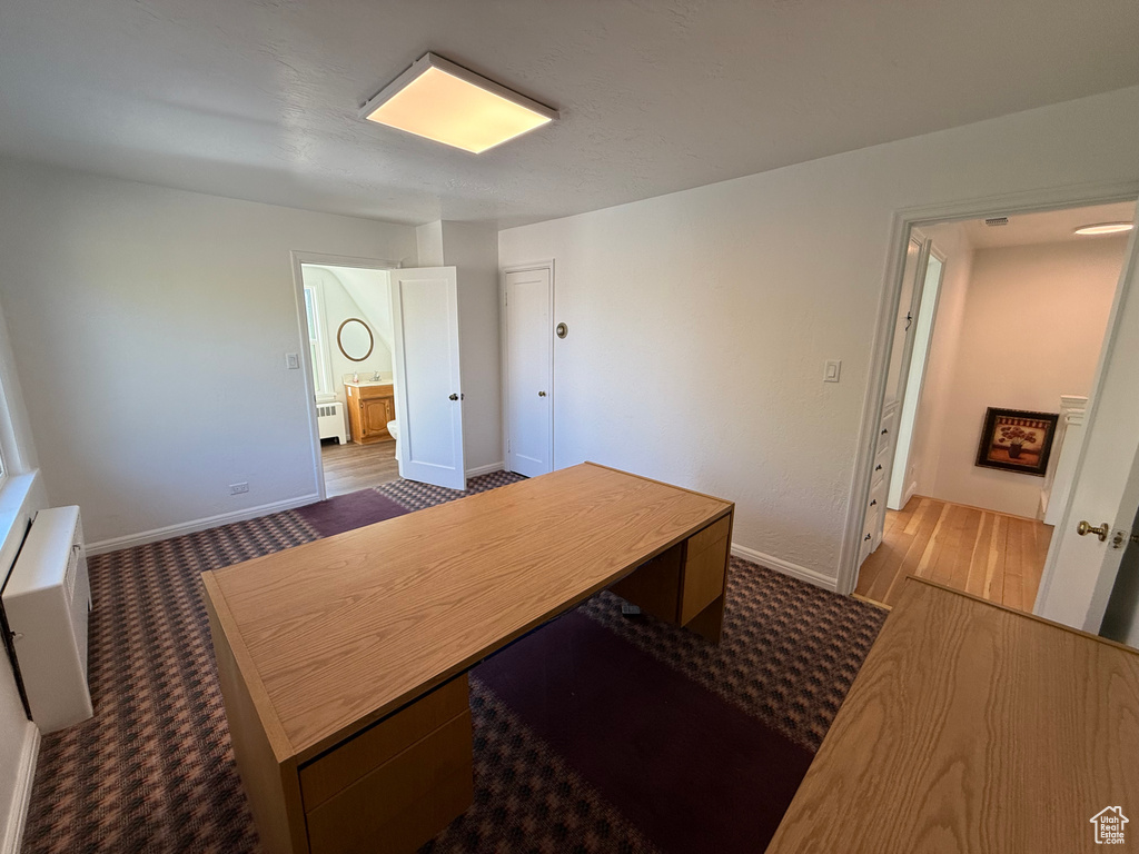 Office area with radiator heating unit and dark hardwood / wood-style flooring