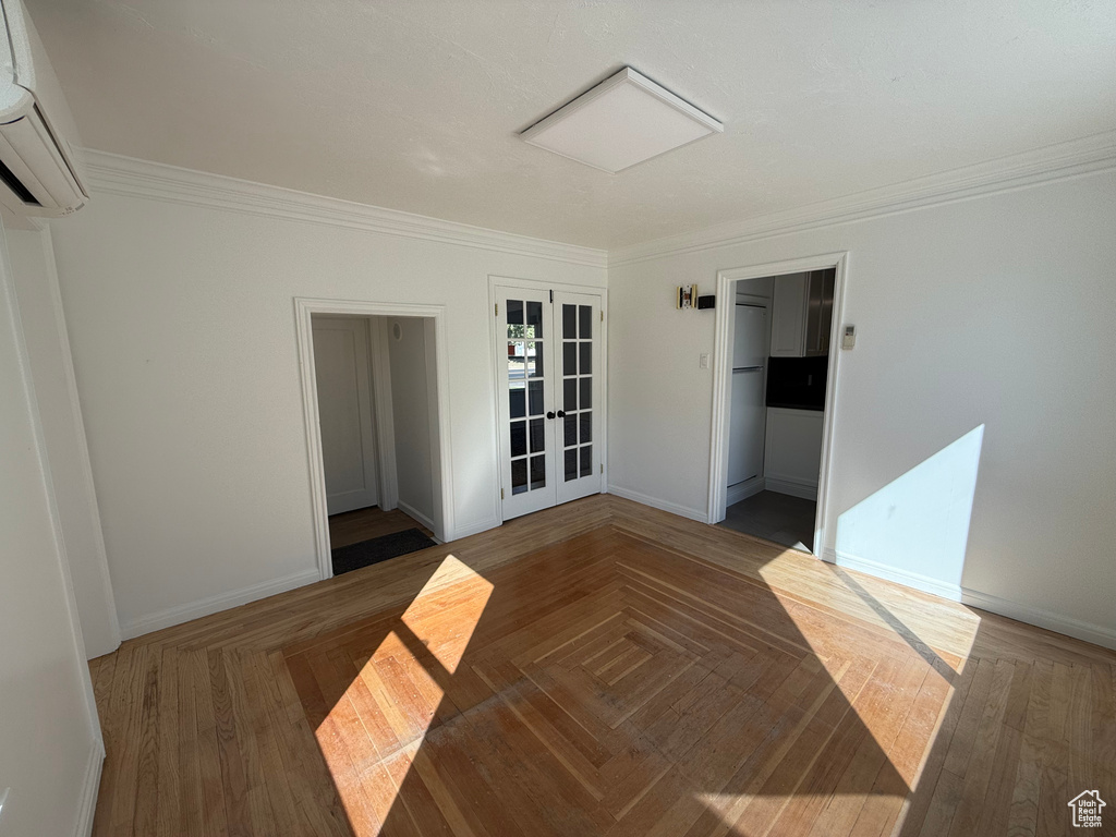 Spare room featuring french doors, crown molding, an AC wall unit, and dark parquet floors