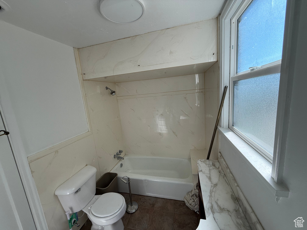 Bathroom featuring toilet, shower / bathing tub combination, and a wealth of natural light