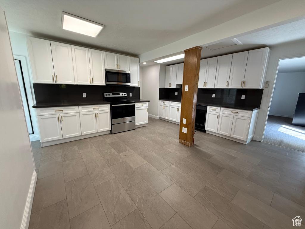 Kitchen featuring decorative backsplash, appliances with stainless steel finishes, and white cabinets