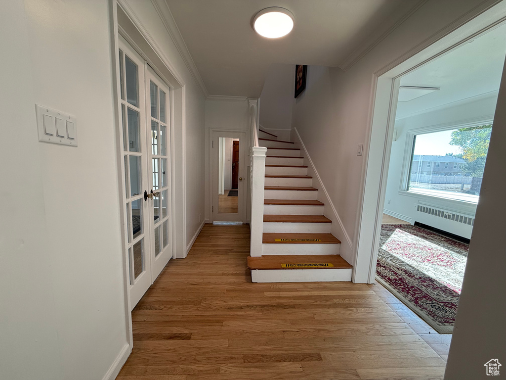 Staircase featuring radiator, hardwood / wood-style flooring, ornamental molding, and french doors