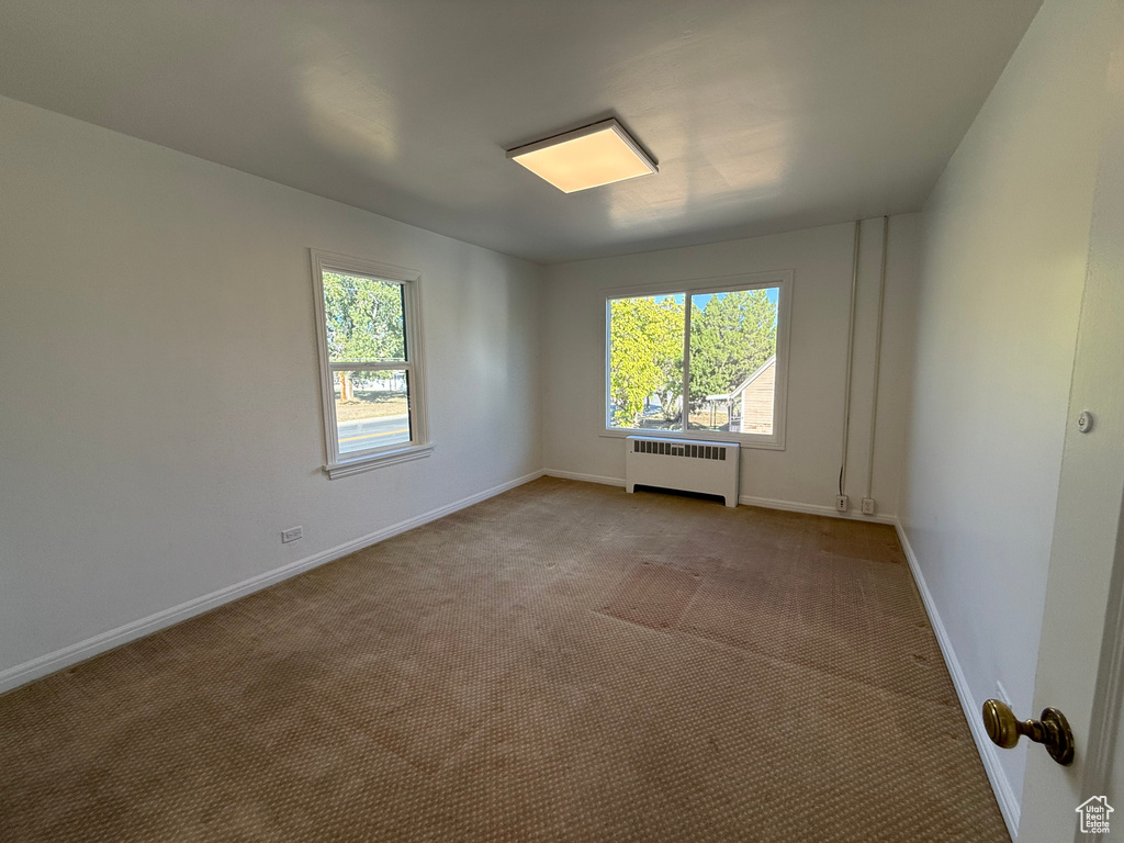 Spare room with radiator heating unit and light colored carpet