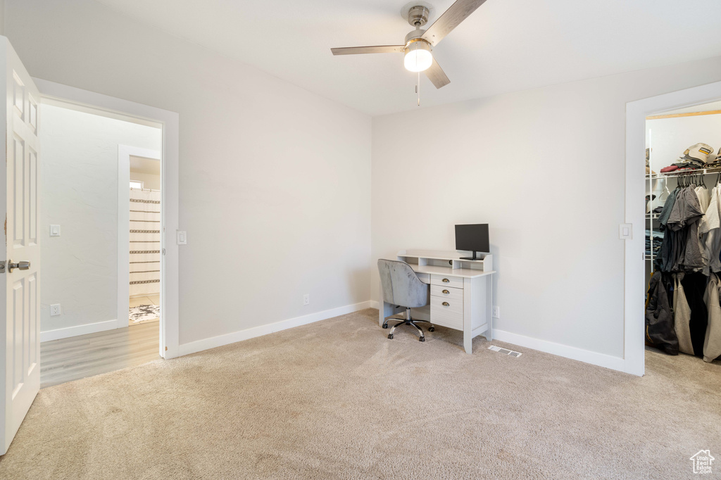 Carpeted office space featuring ceiling fan