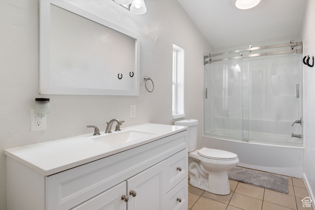 Full bathroom with lofted ceiling, tile patterned floors, toilet, vanity, and enclosed tub / shower combo