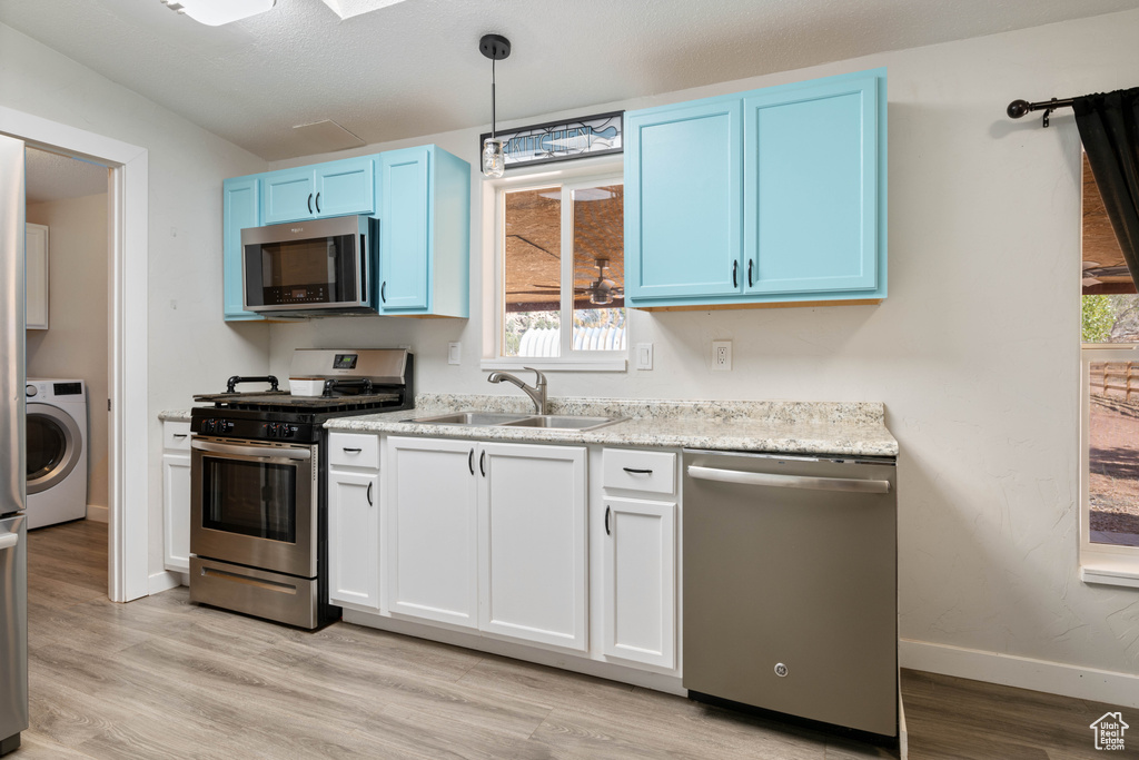 Kitchen featuring washer / dryer, sink, stainless steel appliances, and a wealth of natural light