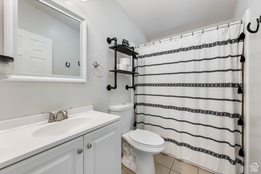 Bathroom featuring tile patterned floors, toilet, curtained shower, vanity, and a textured ceiling