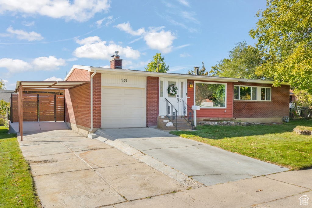 Ranch-style home featuring a front yard, a garage, and a carport