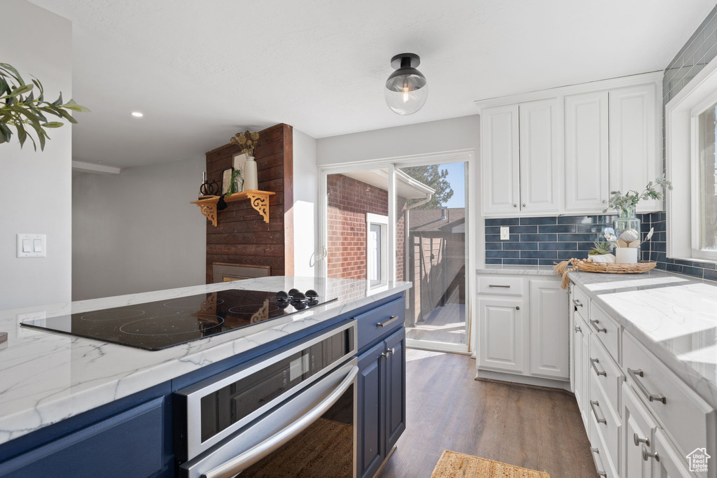 Kitchen with oven, hardwood / wood-style floors, white cabinets, blue cabinetry, and black electric stovetop