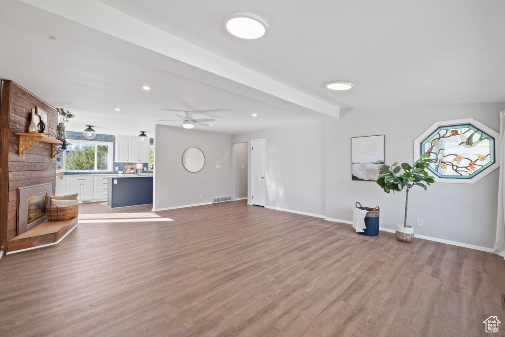 Unfurnished living room featuring hardwood / wood-style floors, a large fireplace, and ceiling fan