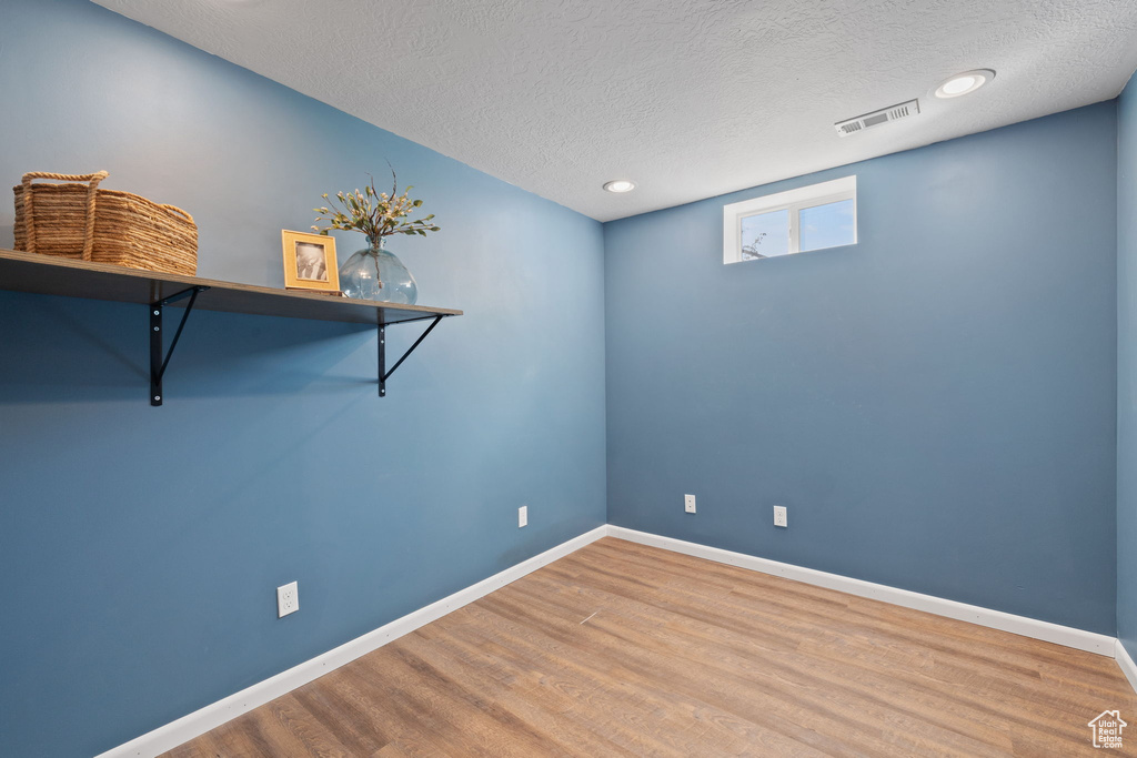 Unfurnished room with hardwood / wood-style floors and a textured ceiling