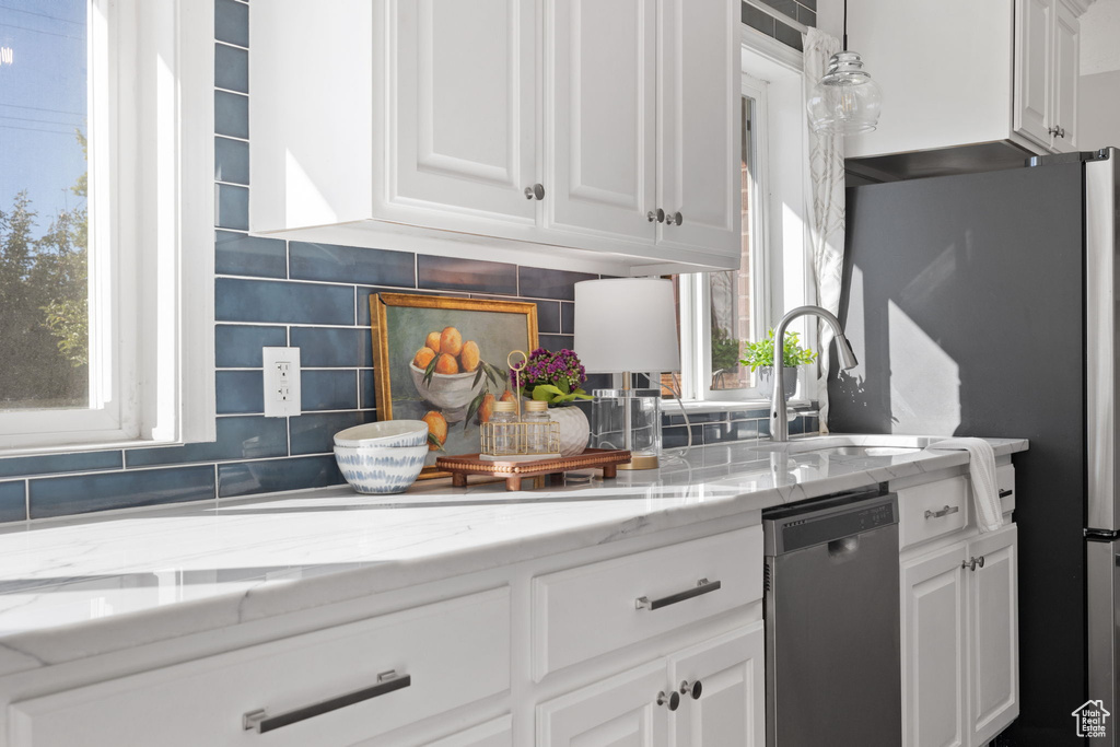 Kitchen with white cabinetry, stainless steel appliances, and a healthy amount of sunlight