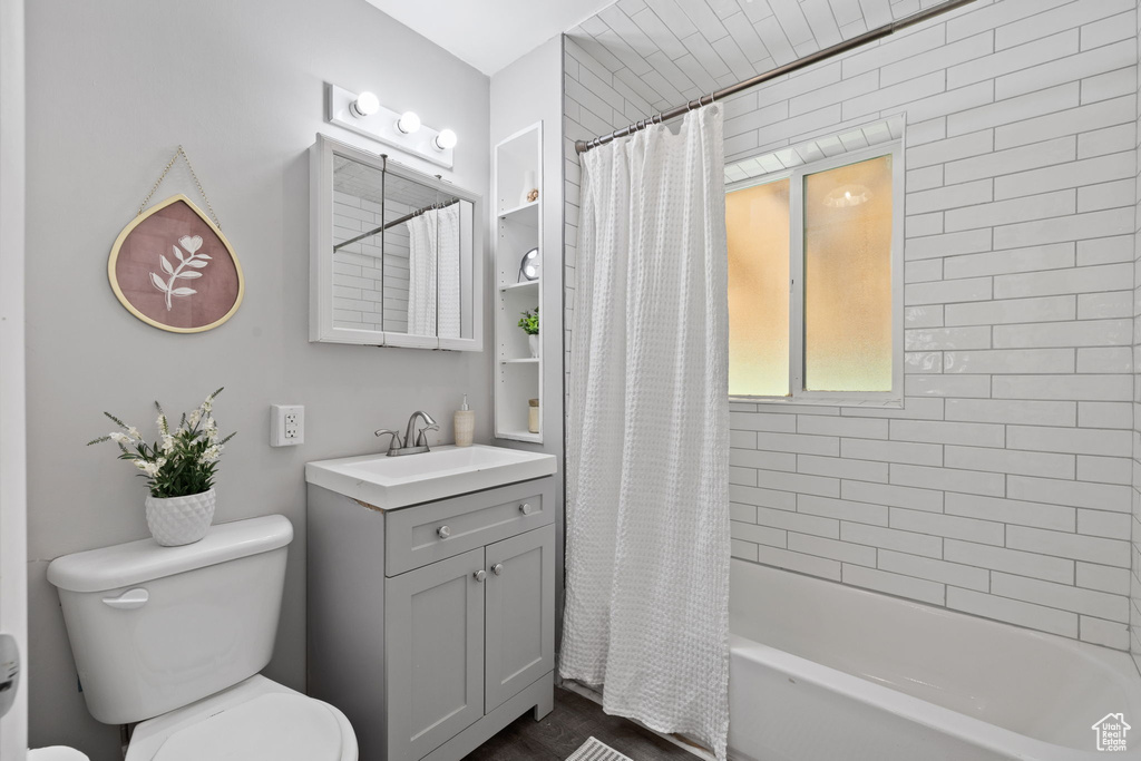 Full bathroom featuring toilet, shower / bath combo with shower curtain, and vanity