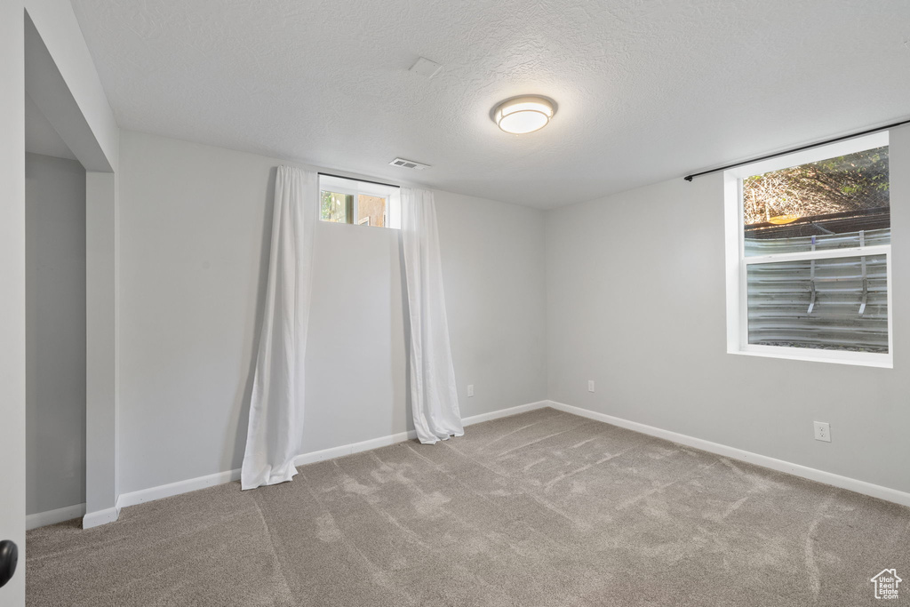 Carpeted empty room featuring a textured ceiling