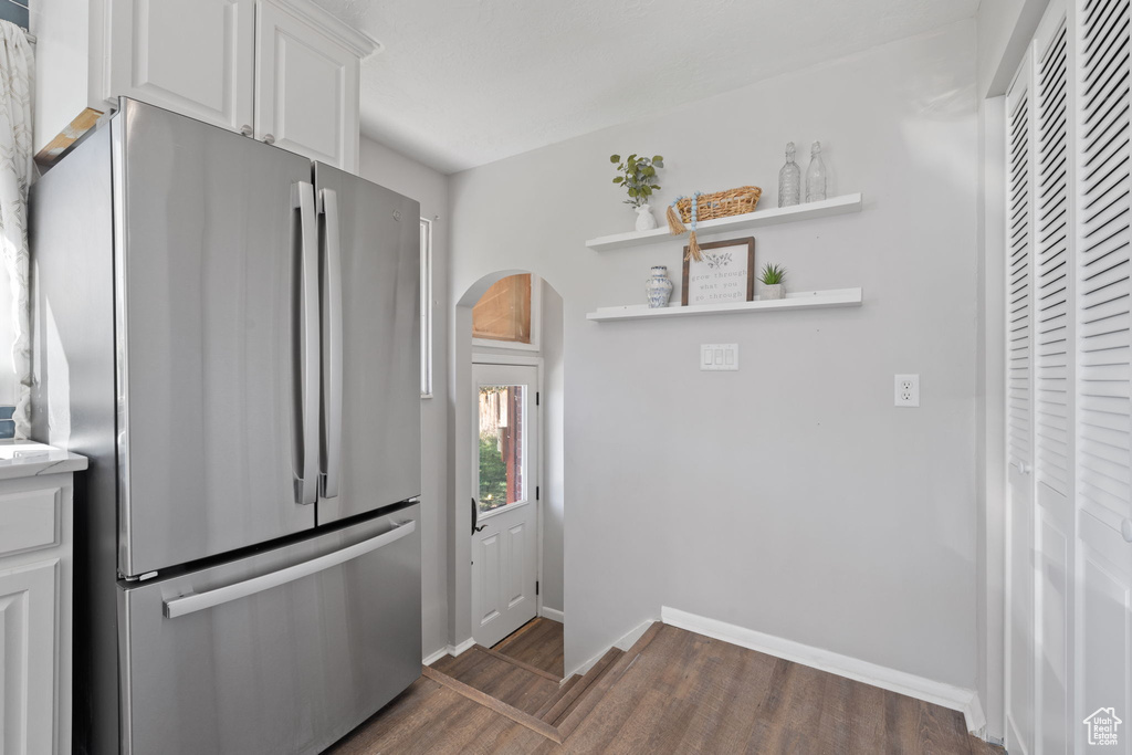 Kitchen featuring dark wood-type flooring, white cabinets, and stainless steel fridge