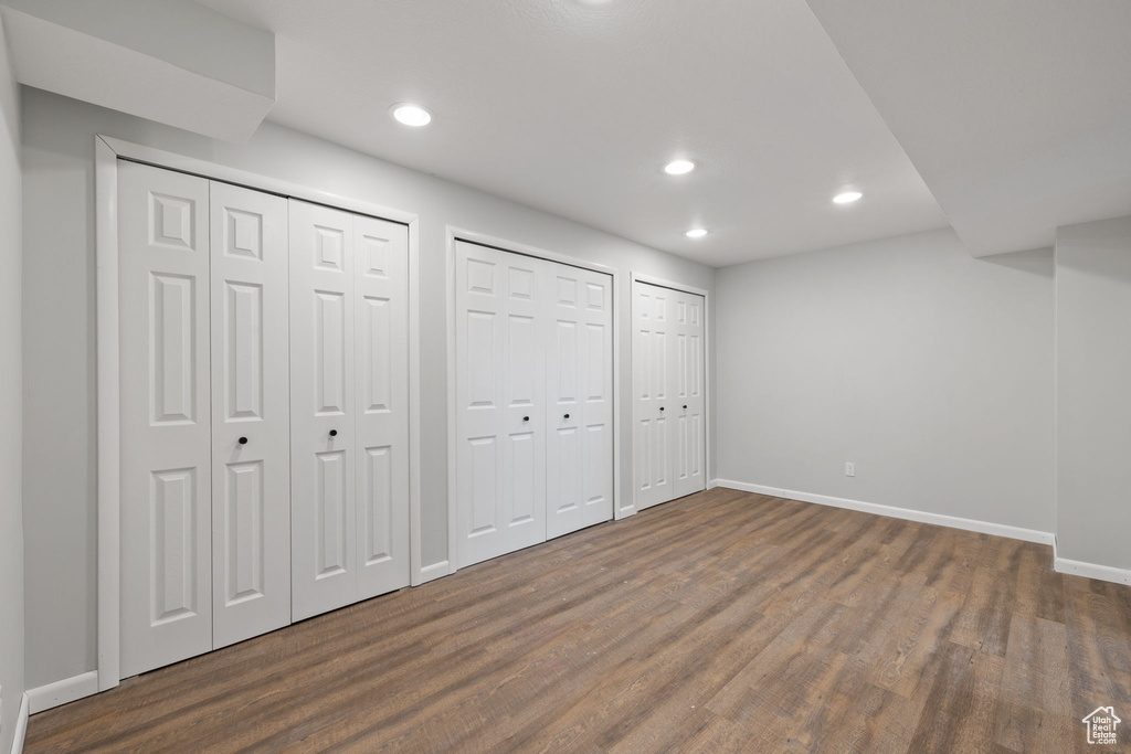 Unfurnished bedroom featuring dark hardwood / wood-style floors and multiple closets