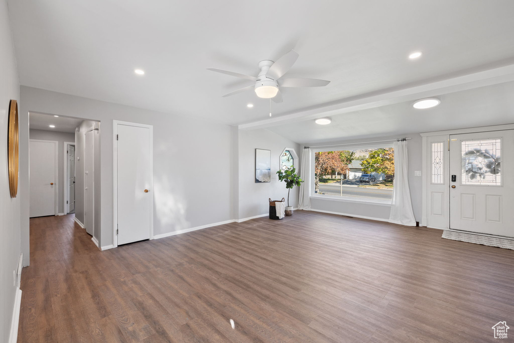 Unfurnished living room with ceiling fan, lofted ceiling, and dark hardwood / wood-style flooring