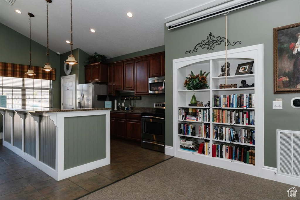 Kitchen with stainless steel appliances, lofted ceiling, a sink, hanging light fixtures, and a breakfast bar area