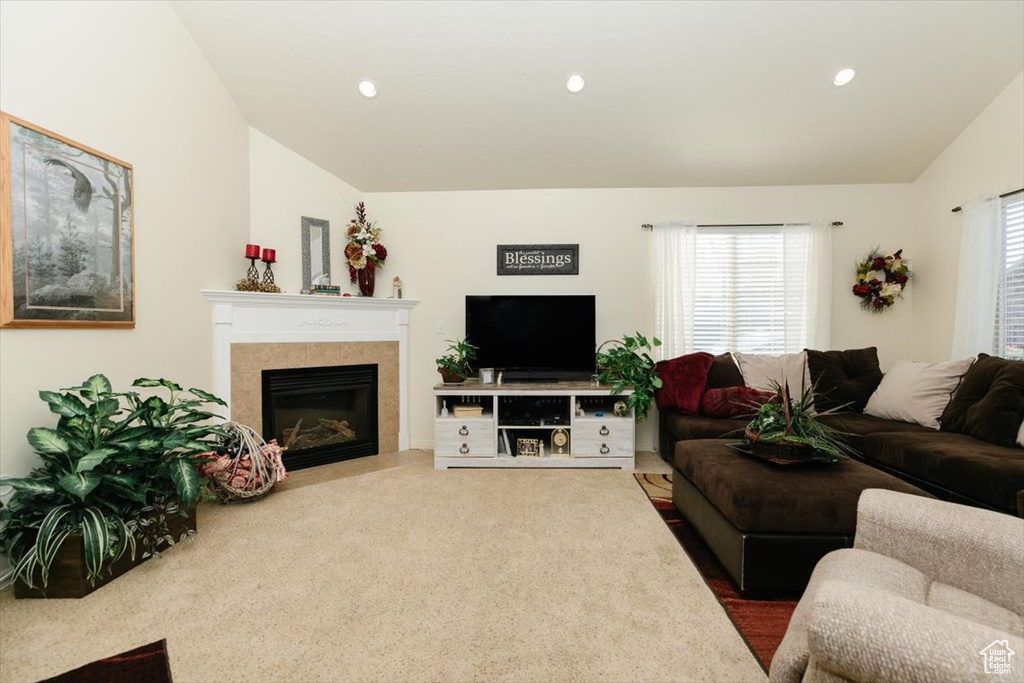 Carpeted living room featuring lofted ceiling, a healthy amount of sunlight, and a fireplace