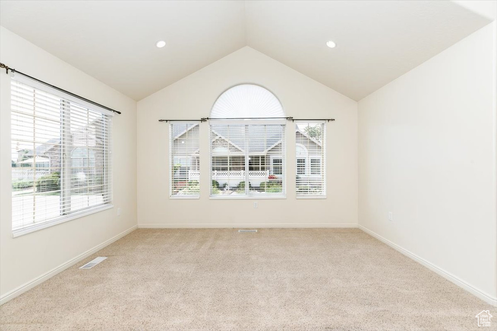 Empty room with light colored carpet, vaulted ceiling, baseboards, and recessed lighting