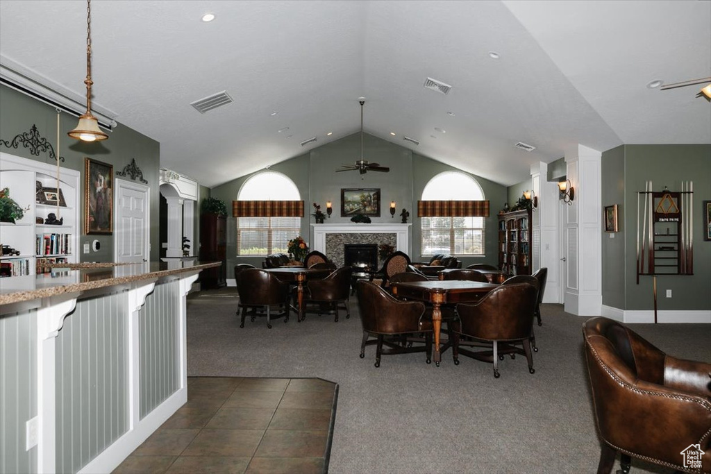 Carpeted dining area with vaulted ceiling and ceiling fan