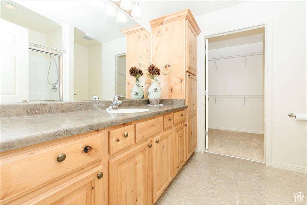Full bath with vanity, a spacious closet, an enclosed shower, and baseboards
