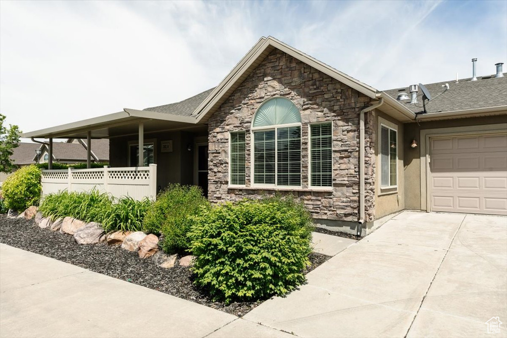 Ranch-style house featuring concrete driveway, stone siding, a garage, and stucco siding