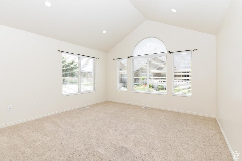 Empty room featuring lofted ceiling, light carpet, baseboards, and recessed lighting