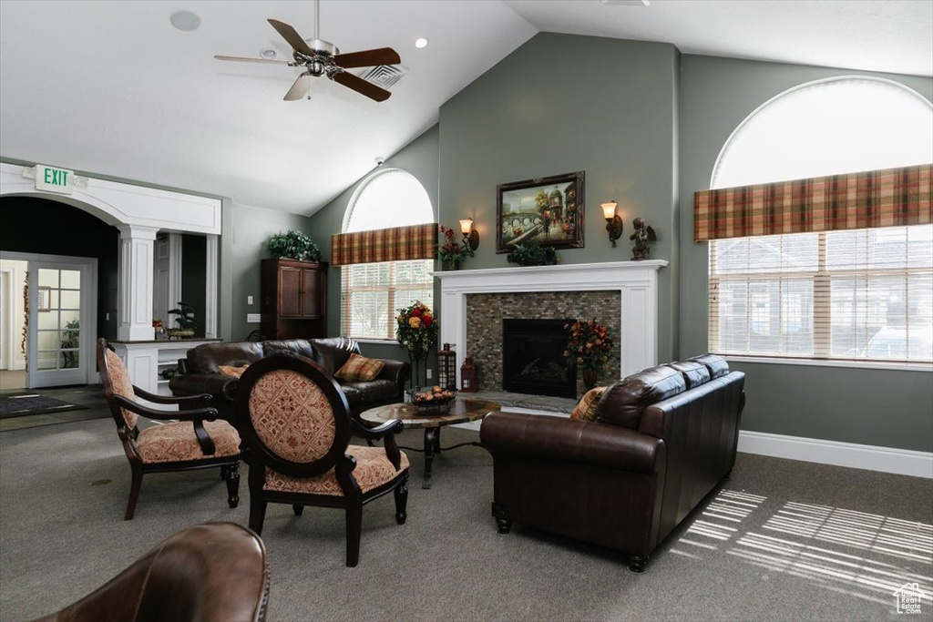 Carpeted living room featuring ceiling fan, high vaulted ceiling, and a wealth of natural light