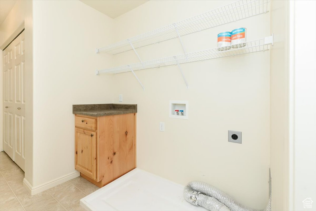 Laundry area featuring hookup for an electric dryer, hookup for a washing machine, light tile patterned floors, and baseboards