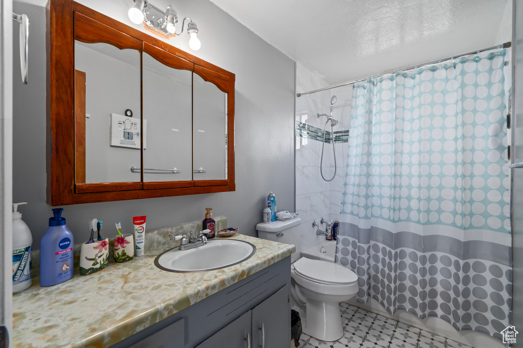 Full bathroom featuring vanity, shower / bathtub combination with curtain, and toilet