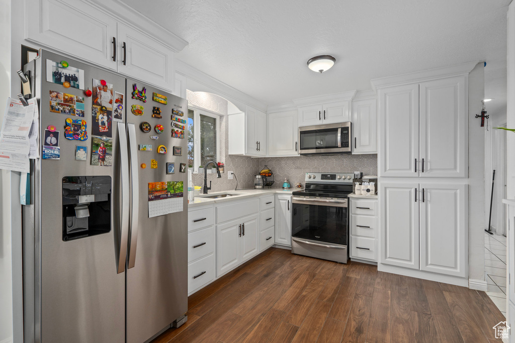 Kitchen featuring white cabinetry, stainless steel appliances, and dark wood-type flooring