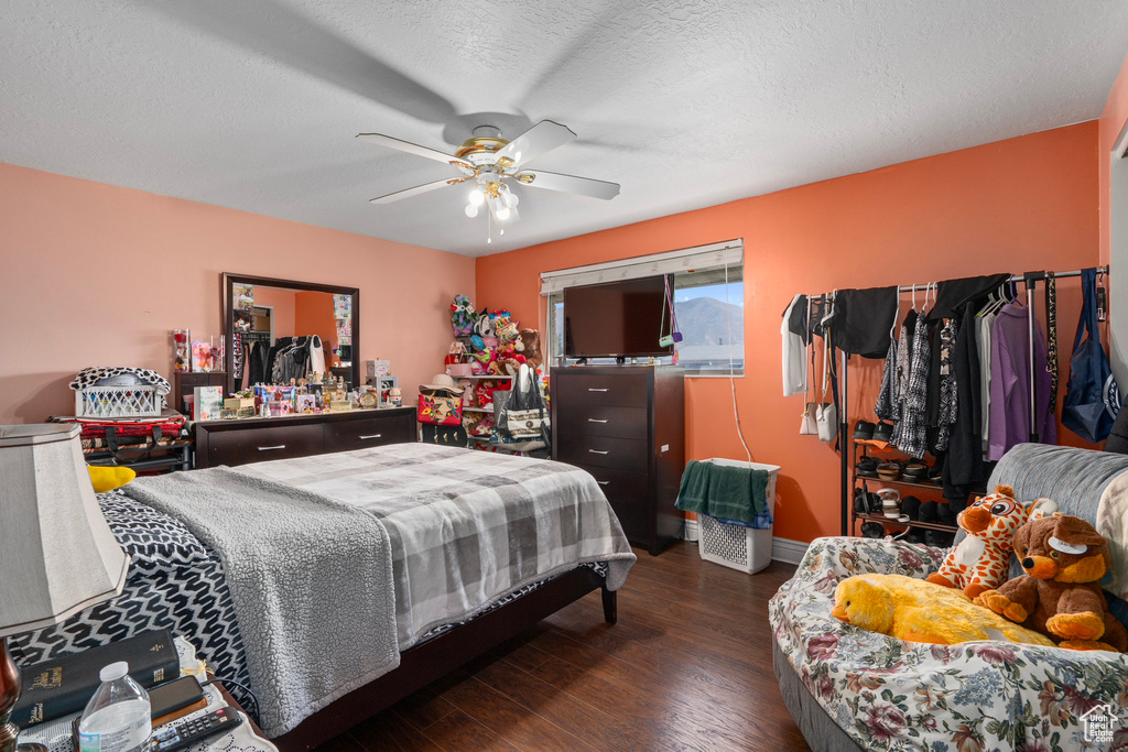 Bedroom with a textured ceiling, dark hardwood / wood-style floors, and ceiling fan