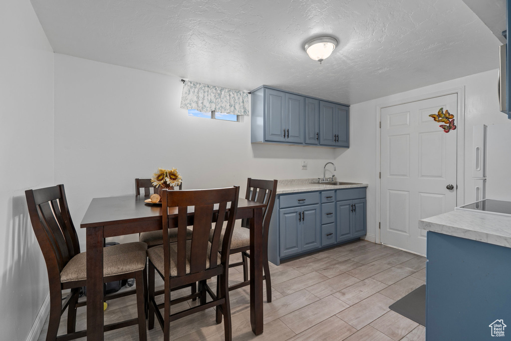 Kitchen featuring blue cabinets, sink, a textured ceiling, and light hardwood / wood-style floors