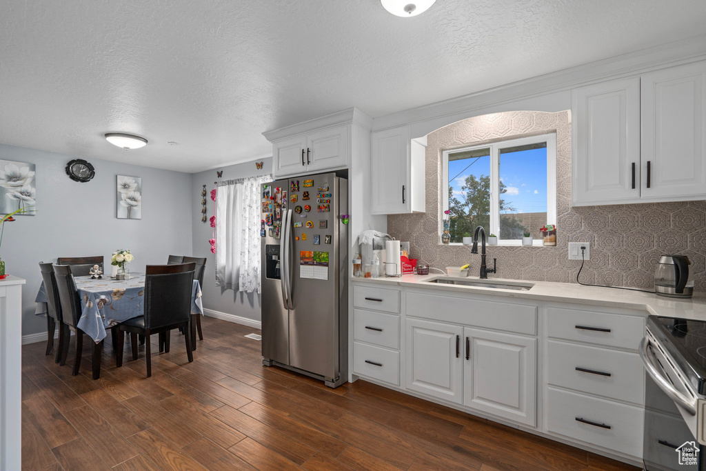 Kitchen featuring appliances with stainless steel finishes, sink, a textured ceiling, white cabinetry, and dark hardwood / wood-style floors