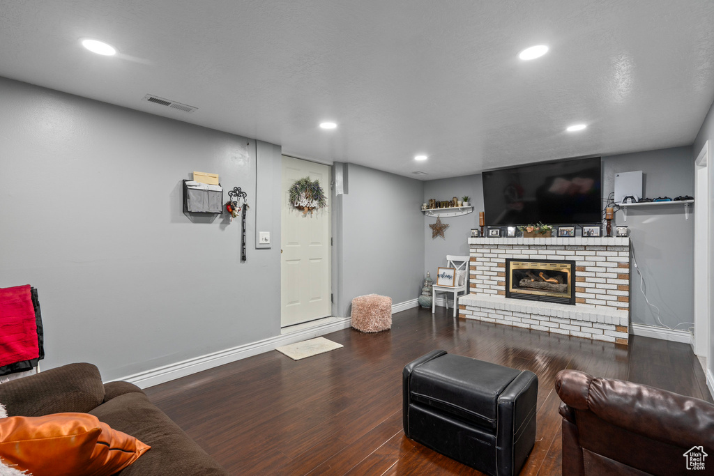 Living room with dark hardwood / wood-style flooring and a fireplace