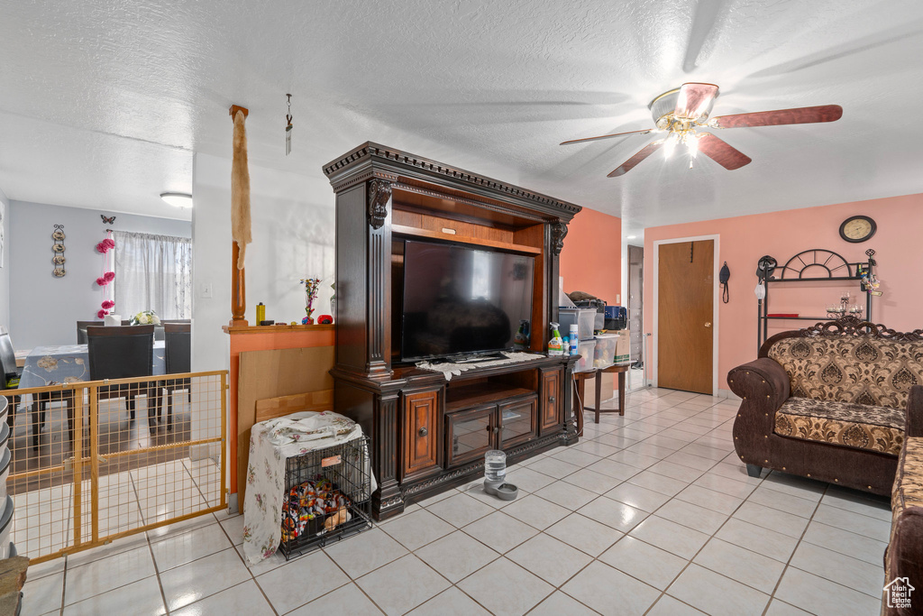 Living room featuring ceiling fan, a textured ceiling, and light tile patterned floors