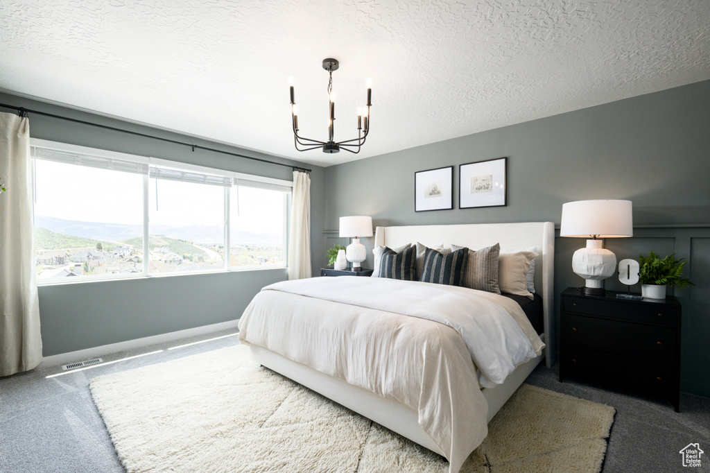 Carpeted bedroom featuring a mountain view, a notable chandelier, and a textured ceiling