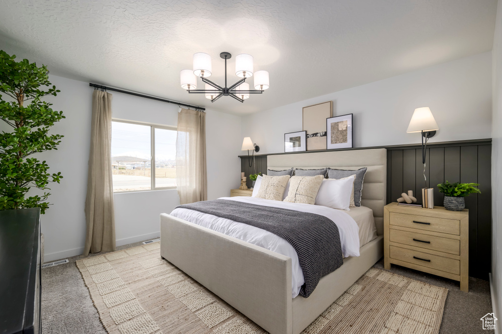 Bedroom featuring light carpet, an inviting chandelier, and a textured ceiling