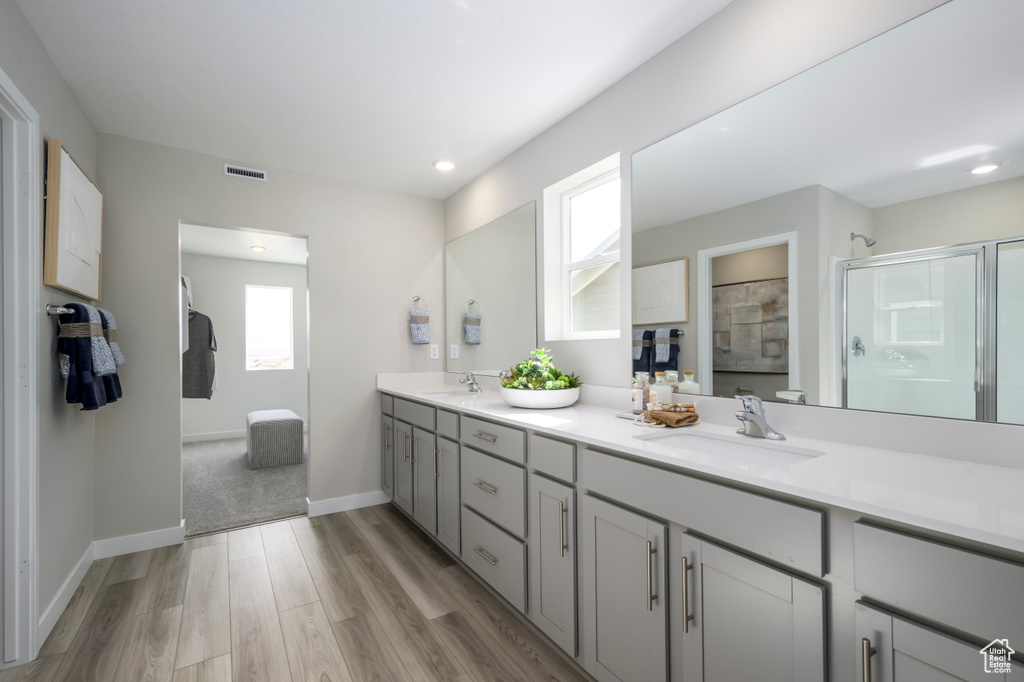 Bathroom featuring vanity, hardwood / wood-style flooring, and a shower with door