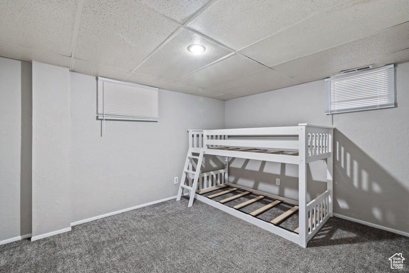 Unfurnished bedroom with a paneled ceiling and dark colored carpet