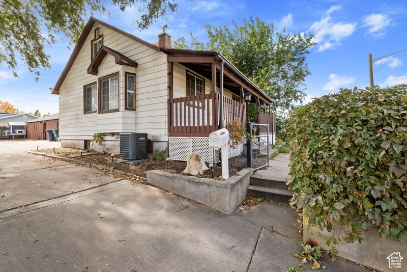 View of side of property with a wooden deck and central AC unit