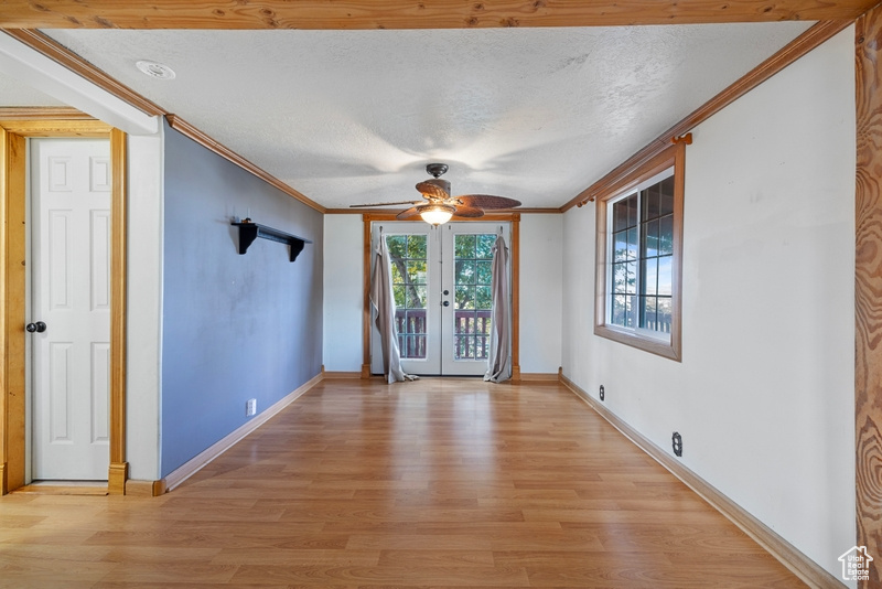 Spare room featuring light hardwood / wood-style flooring, french doors, a textured ceiling, and ceiling fan