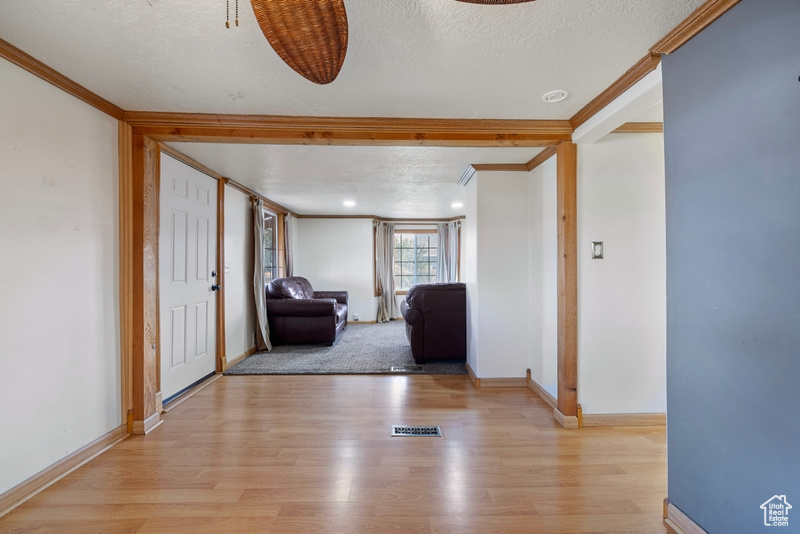 Hall featuring crown molding, a textured ceiling, and light wood-type flooring