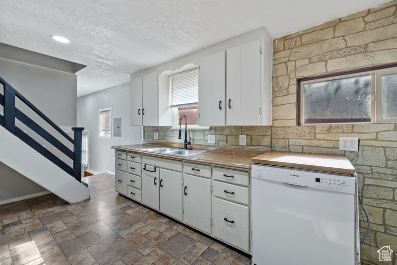 Kitchen featuring decorative backsplash, dishwasher, white cabinets, and sink