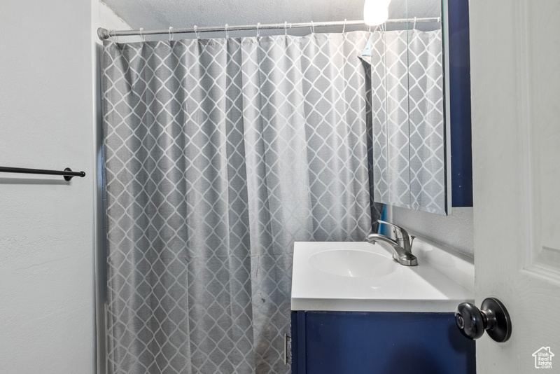 Bathroom with vanity, curtained shower, and a textured ceiling