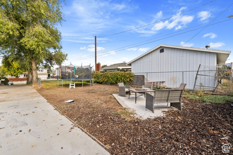 View of yard featuring a trampoline and a patio