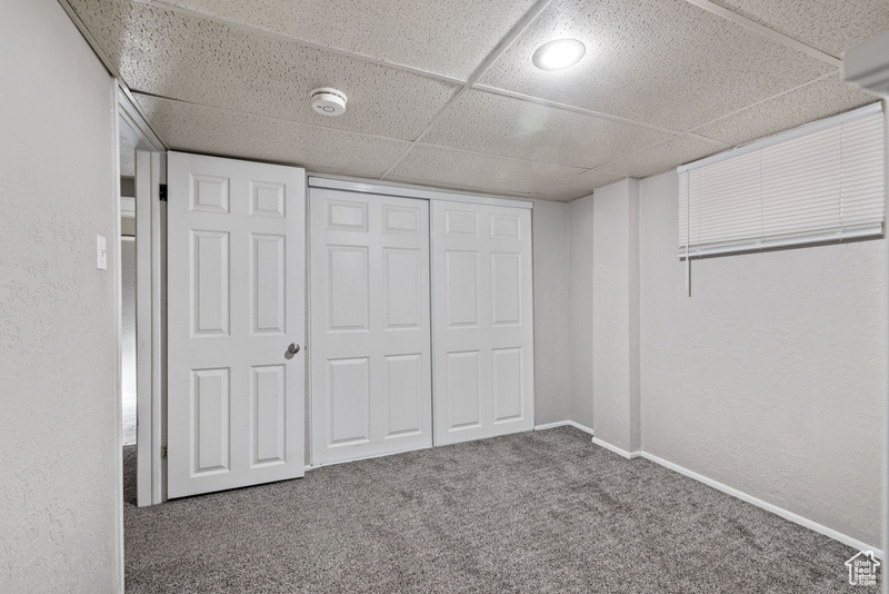 Unfurnished bedroom with a closet, a paneled ceiling, and carpet flooring