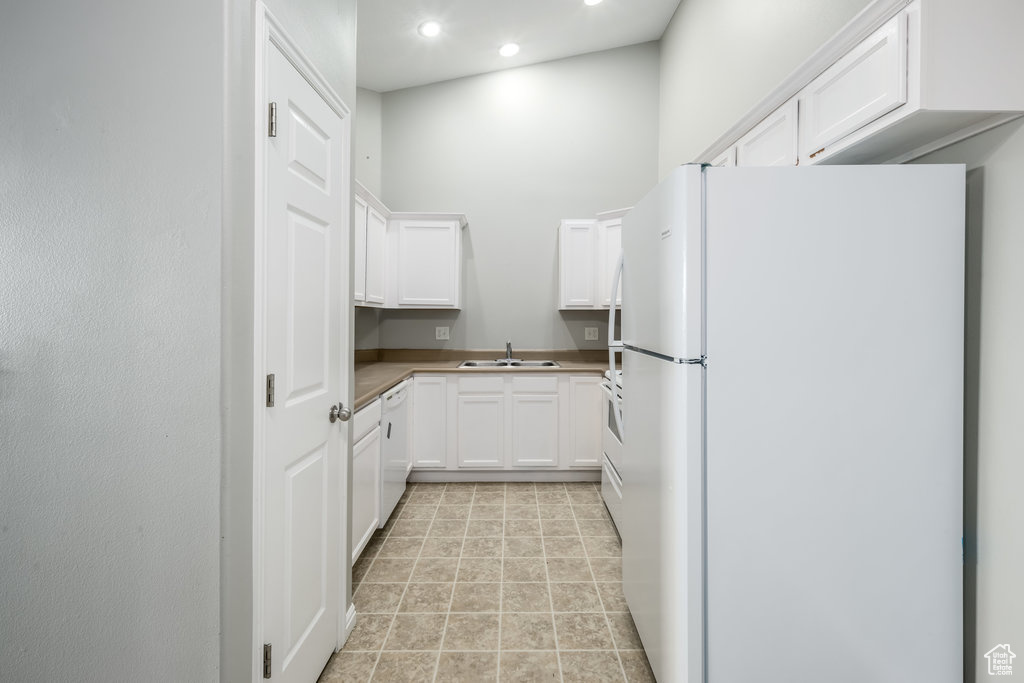 Kitchen featuring sink, white cabinetry, and white appliances