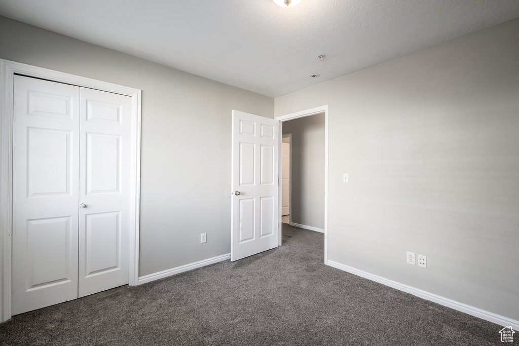 Unfurnished bedroom featuring a closet and dark colored carpet