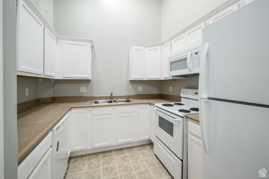 Kitchen with sink, white cabinets, and white appliances